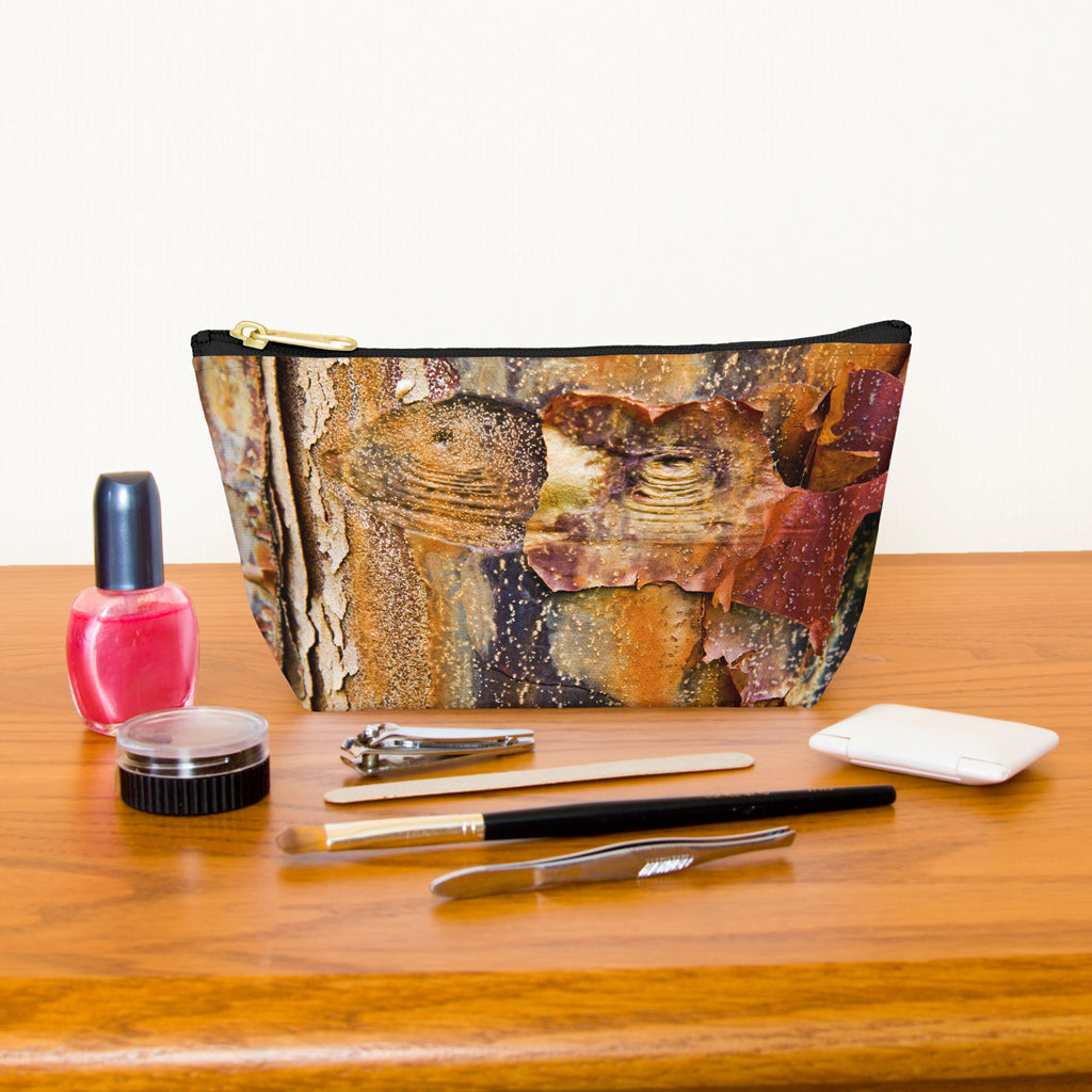 Kit bag with orange bark design next to nail polish, tweezers, nail clippers, makeup brush, blush and eye shadow.