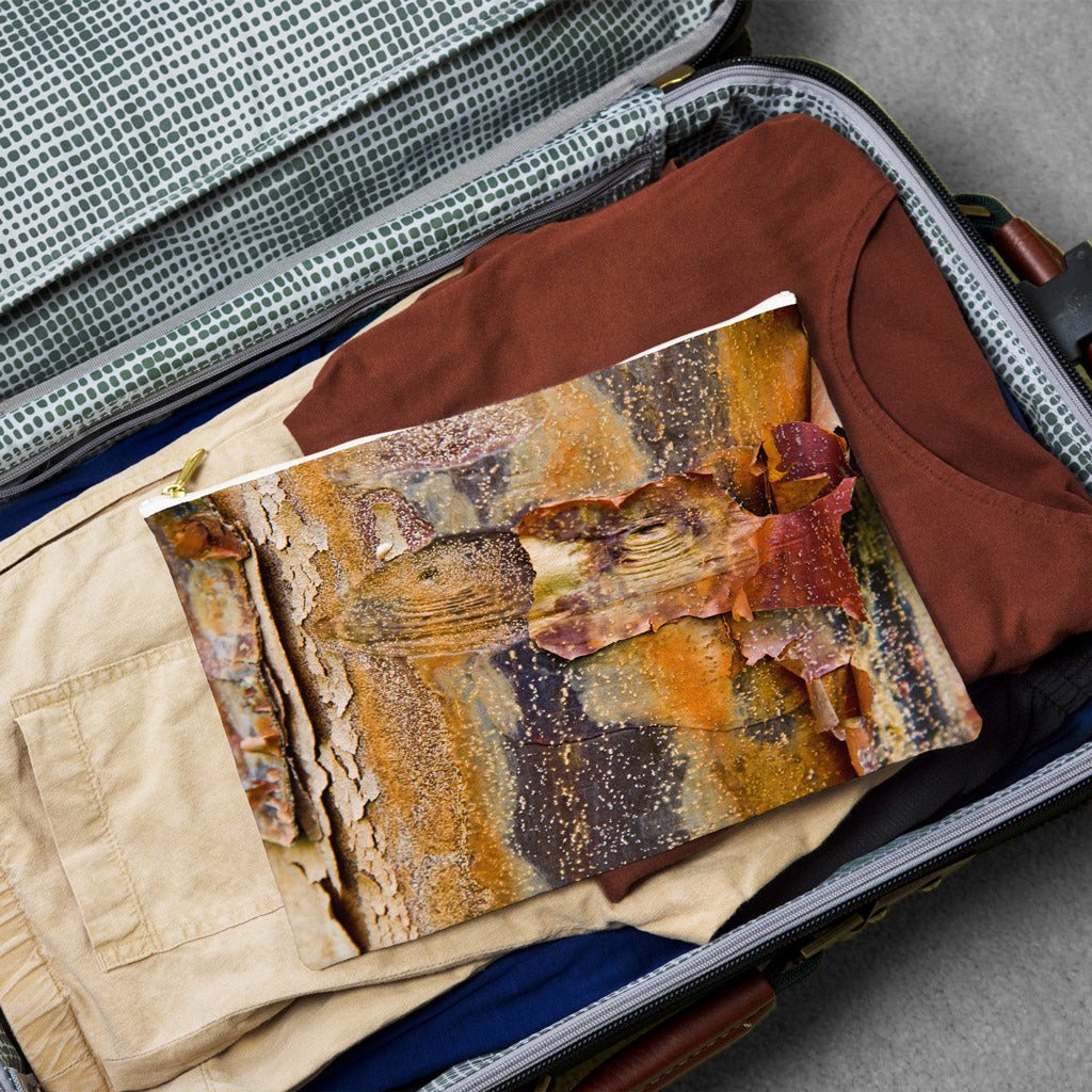 Large pouch with orange bark design lying flat atop the contents of an open suitcase.