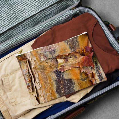 Large pouch with orange bark design lying flat atop the contents of an open suitcase.