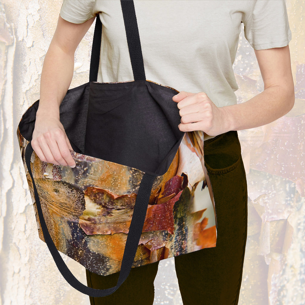 A woman holding open a weekender bag featuring the orange bark design, showcasing the roomy interior.