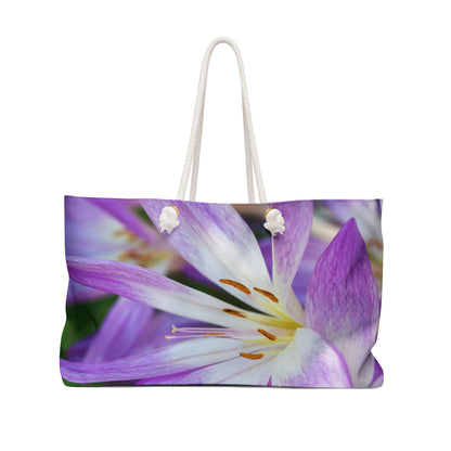 Front view of a beach bag featuring vibrant photo art close up of purple and white flower petals with orange stamen.