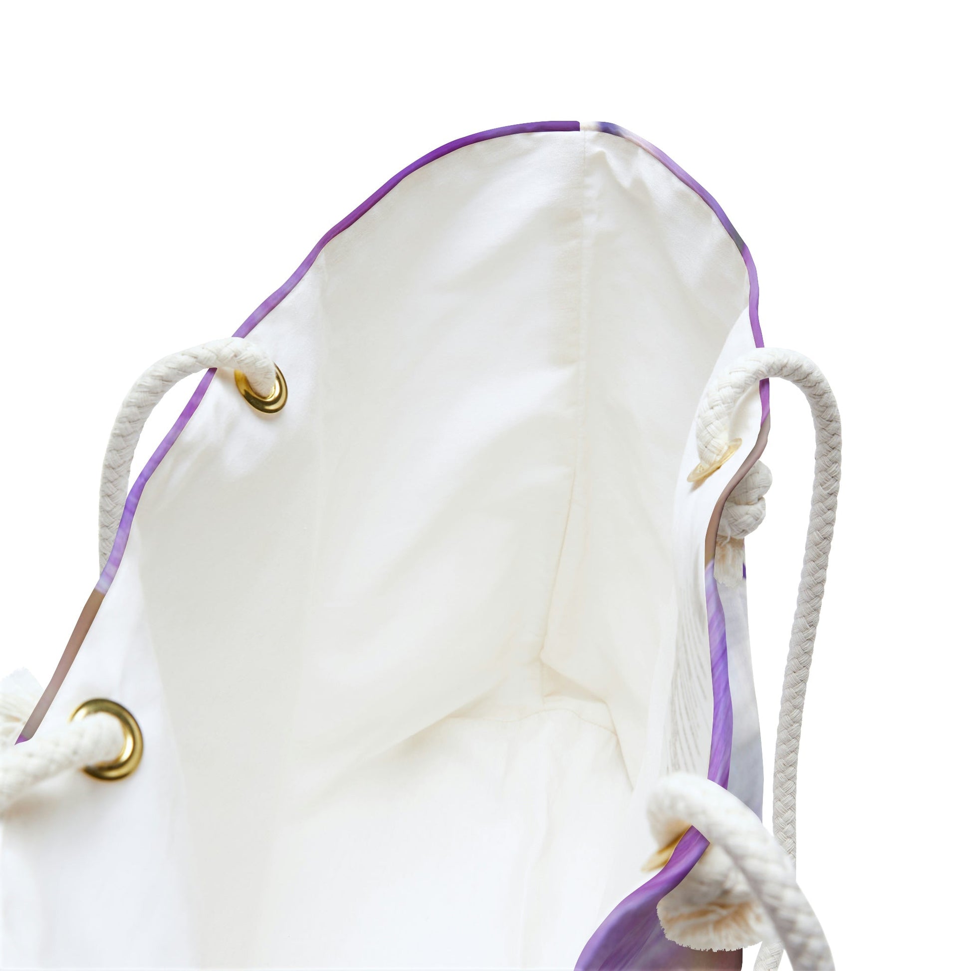 A close up view of the beach bag with purple flowers, orange stamen design shows the braided rope handles with metal grommets.