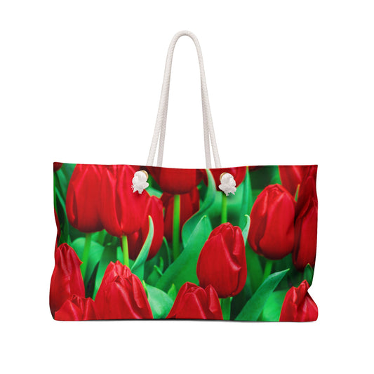 Front view of a beach bag featuring vibrant photo art close up of brilliant red tulips with bright green stems.
