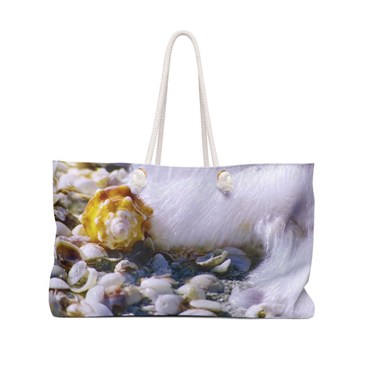 Front view of a beach bag featuring vibrant photo art close up of a shell about to be swept up by a crashing wave.