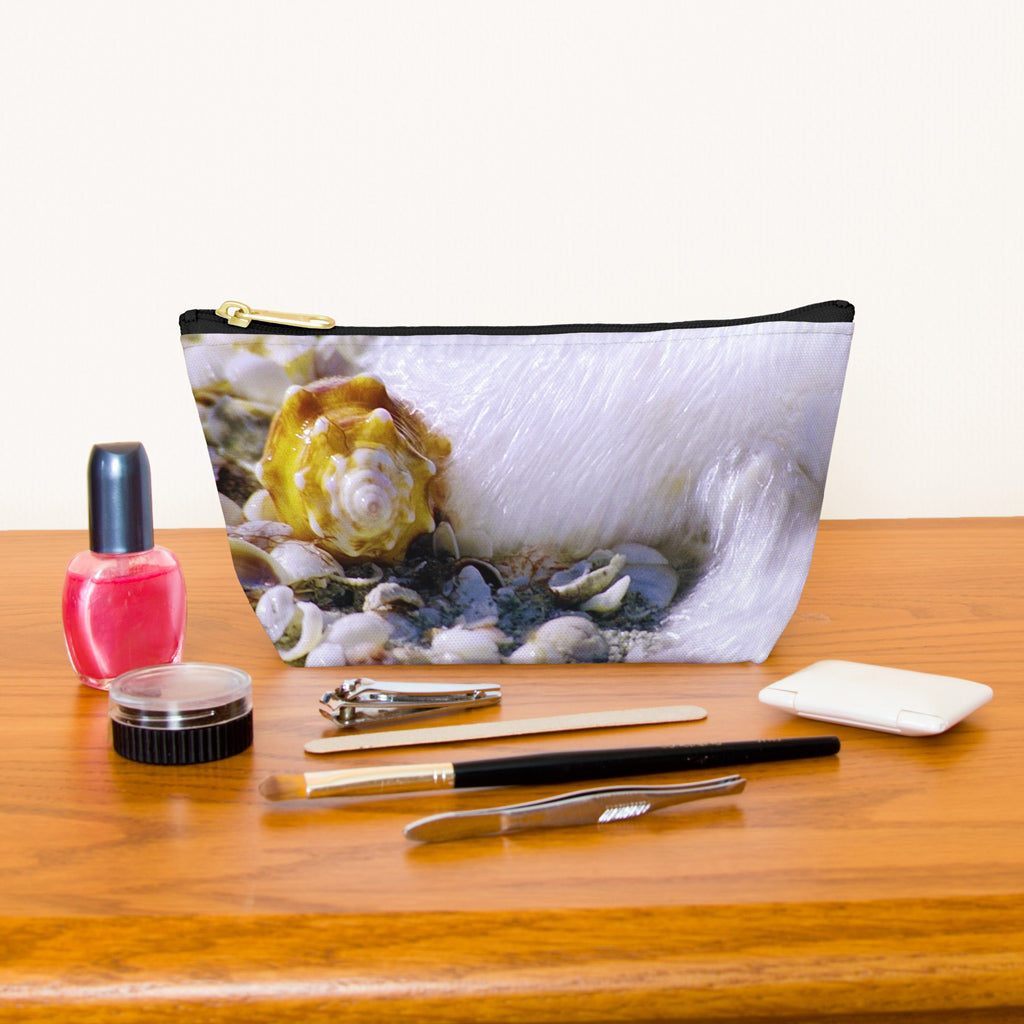 Kit bag with shell in surf design next to nail polish, tweezers, nail clippers, makeup brush, blush and eye shadow.