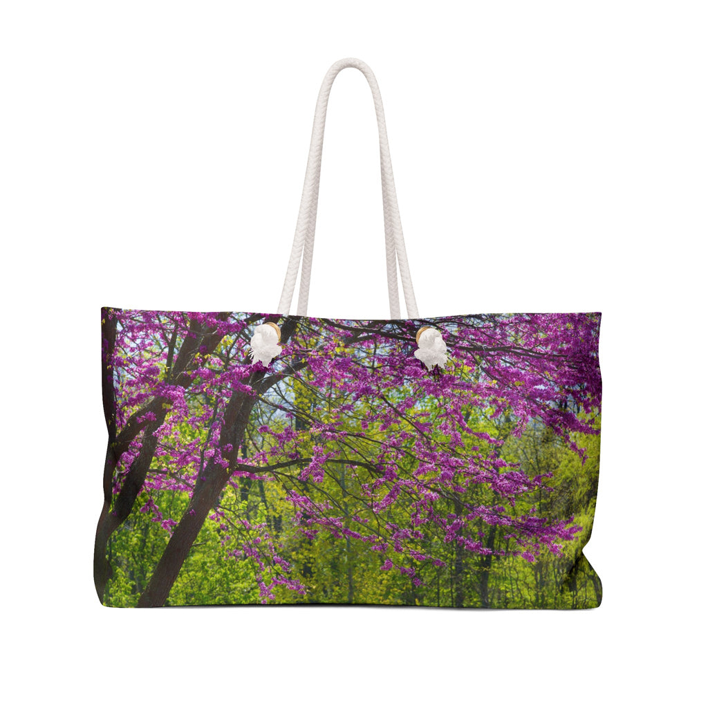 Front view of a beach bag featuring vibrant photo art of a tree filled with violet colored spring buds and blooms.
