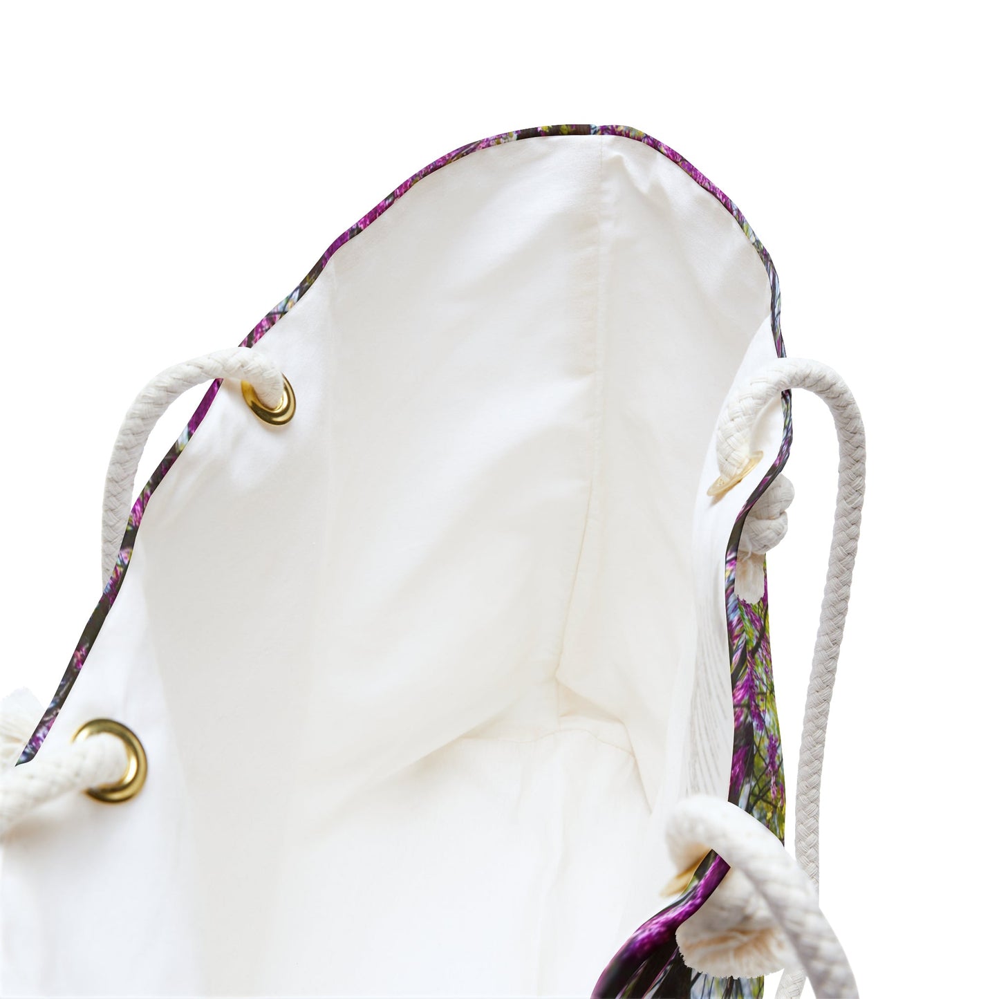 A close up view of the beach bag with tree blossoms design shows the braided rope handles with metal grommets.