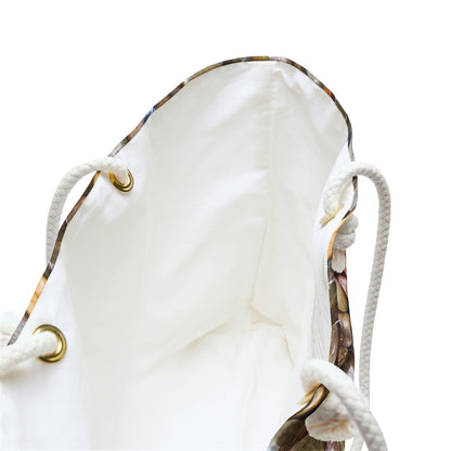 A close up view of the beach bag with pebbles and stones design shows the braided rope handles with metal grommets.