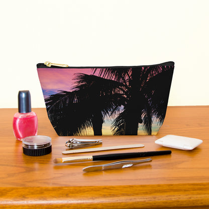 Kit bag with intense sunset design next to nail polish, tweezers, nail clippers, makeup brush, blush and eye shadow.
