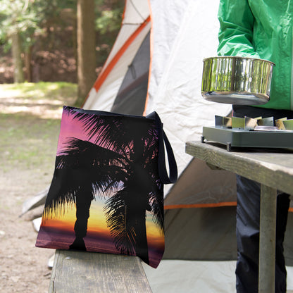 A tote bag featuring the intense sunset design sits on the bench of a campsite picnic table as the camper cooks.