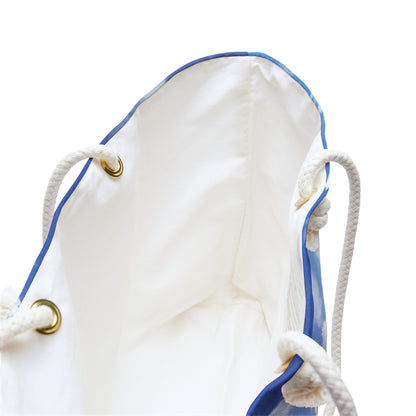 A close up view of the beach bag with beach surf design shows the braided rope handles with metal grommets.