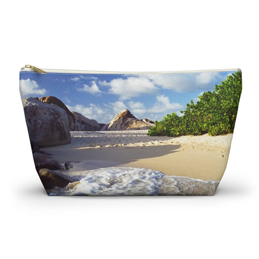 Zippered accessory pouch featuring vibrant photo art of Caribbean beach landscape with surf and huge boulders.