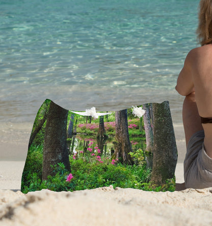 A young woman sitting on the beach with the wetland design beach bag by her side.