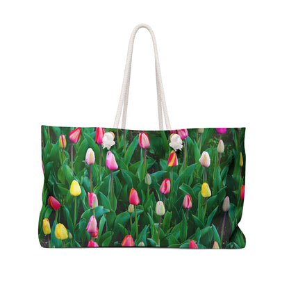 Front view of a beach bag featuring vibrant photo art close up of multi colored tulip buds days from full bloom.