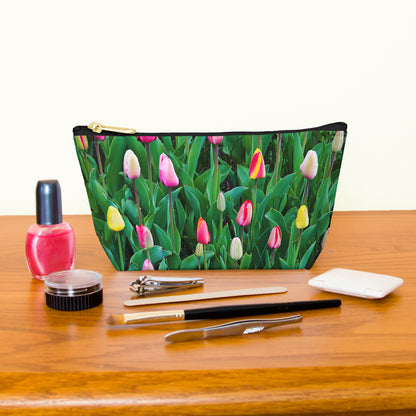 Kit bag with multi colored tulips design next to nail polish, tweezers, nail clippers, makeup brush, blush and eye shadow.