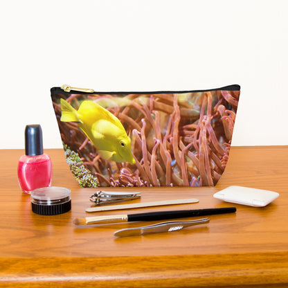 Kit bag with yellow fish design next to nail polish, tweezers, nail clippers, makeup brush, blush and eye shadow.